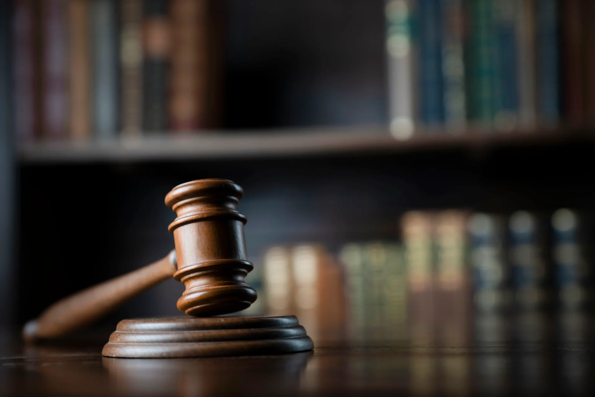 Gavel on desk with blurred books background.
