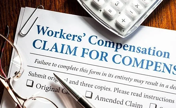 A pen and calculator on a workers' compensation claim form.